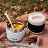 Two food containers are placed on a textured fabric outdoors, with fallen leaves in the background. Produktbild-Vorschau
