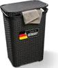 A black laundry basket with a lid and two folded towels hanging from the edge. A "Made in Germany" label is visible on the front. Produktbild-Vorschau