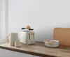 A toaster, kettle, and bowl with bread on a wooden countertop. Anteprima dell’immagine prodotto