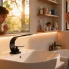 A man brushing his teeth in a modern bathroom with a black faucet. Produktbild-Vorschau