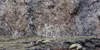 A rocky cliff face with sparse vegetation in the foreground. Náhľad obrázku produktu