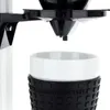 A close-up view of a Moccacoffee machine's drip mechanism and a white mug with a black textured sleeve. Produktbild-Vorschau