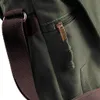 A close-up view of a green canvas bag, showing a zipper with a gold pull tab and a brown strap. Anteprima dell’immagine prodotto
