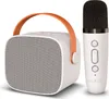 A white portable Bluetooth speaker with an orange handle and a white wireless microphone are displayed against a white background. Náhľad obrázku produktu