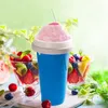 A blue slushy maker cup filled with pink slushy, placed in front of bowls of fresh fruit salad. Podgląd zdjęcia produktu