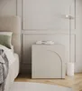 A close-up view of a modern bedroom nightstand with a lamp and books. Produktbild-Vorschau