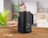 A black electric kettle is shown steaming on a wooden table in a bright kitchen setting. Podgląd zdjęcia produktu
