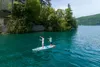 Two people paddleboarding on a lake with a building and trees in the background. Voir les images du produit