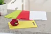Four plastic cutting boards in different colors (green, red, white, yellow) are arranged on a countertop. A red bell pepper is placed on the yellow cutting board. Produktbild-Vorschau