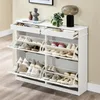 A white shoe cabinet with multiple shelves and drawers, filled with various shoes. Produktbild-Vorschau