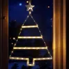 A Christmas tree-shaped light decoration hanging in a window at night. Voir les images du produit