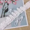 A close-up of white curtain hooks attached to a ruffled curtain tape, with a blurred floral background and text from a newspaper or book. Produktbild-Vorschau