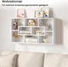 A white wall-mounted shelf unit filled with decorative items and books, positioned above a sofa. Produktbild-Vorschau