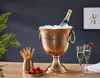 A champagne cooler filled with ice and a bottle of champagne, accompanied by champagne flutes, strawberries, and breadsticks, set on a wooden table. Produktbild-Vorschau
