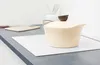 A beige pot with a brown lid sits on a white mat on a dark countertop. Náhled obrázku produktu