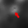 A close-up view of a textured black surface with a dent and a red arrow pointing to it. Produktbild-Vorschau