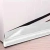 A close-up view of a white door draft stopper with a black strip, placed on a wooden floor against a white wall. Náhled obrázku produktu