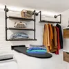 A laundry room or utility space with shelves, hanging clothes, and an ironing board. Produktbild-Vorschau