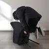 A person in a black coat is interacting with a black chair, appearing to be assembling or disassembling it. Voir les images du produit