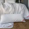 A white pillow is laid out on a wooden floor, with bedding in the background. Produktbild-Vorschau