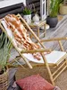 A cozy outdoor seating area with a bamboo deck chair, a patterned blanket, and decorative pillows. Produktbild-Vorschau