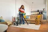 A woman is vacuuming a rug in a living room. Anteprima dell’immagine prodotto