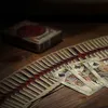 A close-up of a deck of playing cards fanned out on a wooden surface, with the deck box in the background. Produktbild-Vorschau