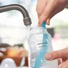 A person is washing a baby bottle under a faucet with a bottle brush. Produktbild-Vorschau