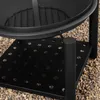 A close-up view of the base of a black metal fire pit, showing its perforated shelf and legs resting on a bed of gravel. Produktbild-Vorschau