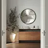 A round wall mirror is mounted above a wooden sideboard in a hallway, with a large potted plant to the left. Produktbild-Vorschau