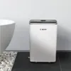 A white Bosch dehumidifier is placed on a dark tiled floor next to a white bathtub and a decorative area of white stones. Produktbild-Vorschau