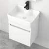A white ceramic sink with a black faucet mounted on a white cabinet against a marble-tiled wall. Produktbild-Vorschau