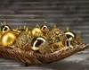 A collection of golden Christmas ornaments in a woven basket. Náhled obrázku produktu
