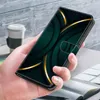 A hand holding a phone case with a green and gold abstract design. In the background, a coffee cup and a book are visible. Produktbild-Vorschau