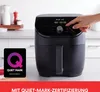 A person's hand is shown interacting with the control panel of a black air fryer, which is placed on a kitchen counter. Produktbild-Vorschau