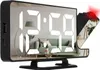 A digital alarm clock with a mirrored display showing a reflection of a living room. Náhled obrázku produktu