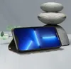 A smartphone in a flip case is displayed on a surface with stacked stones and a plant in the background. Produktbild-Vorschau