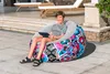 A young boy is sitting on an inflatable chair outdoors. Produktbild-Vorschau