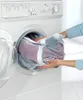 A person is putting a laundry bag filled with clothes into a washing machine. Anteprima dell’immagine prodotto