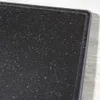 A close-up view of a black speckled cutting board with a raised edge, resting on a light wooden surface. Náhľad obrázku produktu