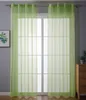A room interior with a large window covered by light green sheer curtains.