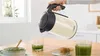A hand is pouring hot water from a Bosch electric kettle into a glass containing a green beverage. Anteprima dell’immagine prodotto