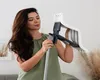 A woman is holding and adjusting a mop in a home setting. Produktbild-Vorschau