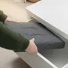 A person's hands are shown placing a gray storage ottoman into a white drawer or compartment. Anteprima dell’immagine prodotto