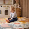 A baby playing on a play mat in front of a toy kitchen. Podgląd zdjęcia produktu