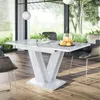 A modern dining room with a white high-gloss extendable table and chairs, set against a backdrop of large windows overlooking a garden. Produktbild-Vorschau