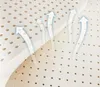 A close-up, angled view of a white, perforated material, likely a mattress or foam padding, with stylized transparent arrows indicating airflow or breathability. Podgląd zdjęcia produktu