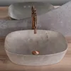 A marble sink with a copper faucet on a wooden surface. Náhled obrázku produktu