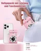 A hand is placing a small pink digital camera into a pocket, with a smartphone and another pink camera visible in the foreground. Produktbild-Vorschau