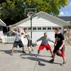 Four men playing basketball in a driveway in front of a garage. Produktbild-Vorschau